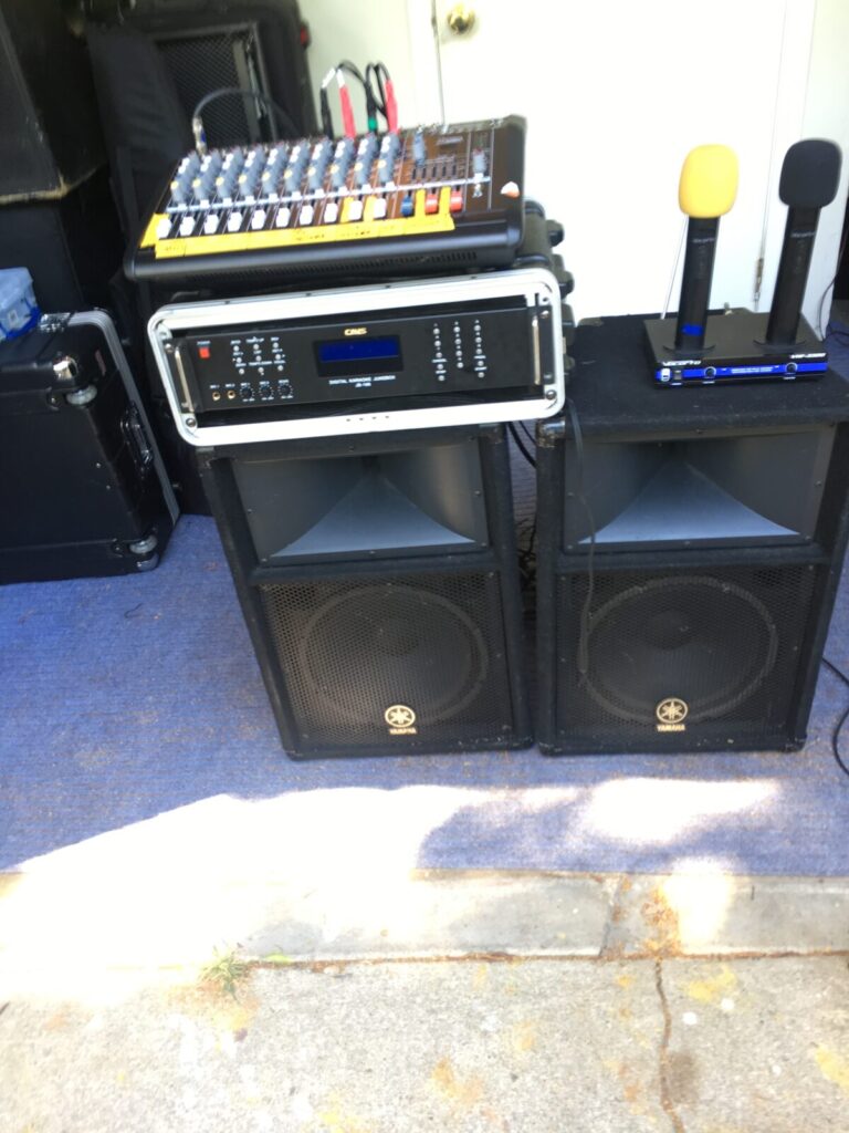 Audio equipment setup for an outdoor event, including a mixer, amplifier, microphones, and speakers.